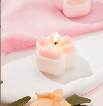 Low Temperature BDSM Cat Claw Candle burning brightly on a soft surface, showcasing its unique cat claw design.