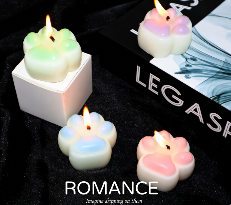 Low Temperature BDSM Cat Claw Candle set on a black surface, featuring colorful paw-shaped candles with lit wicks.