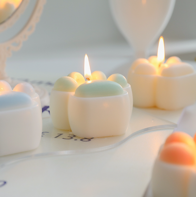 Low Temperature BDSM Cat Claw Candle lit amongst pastel colored candles, ideal for intimate wax play at a safe temperature.