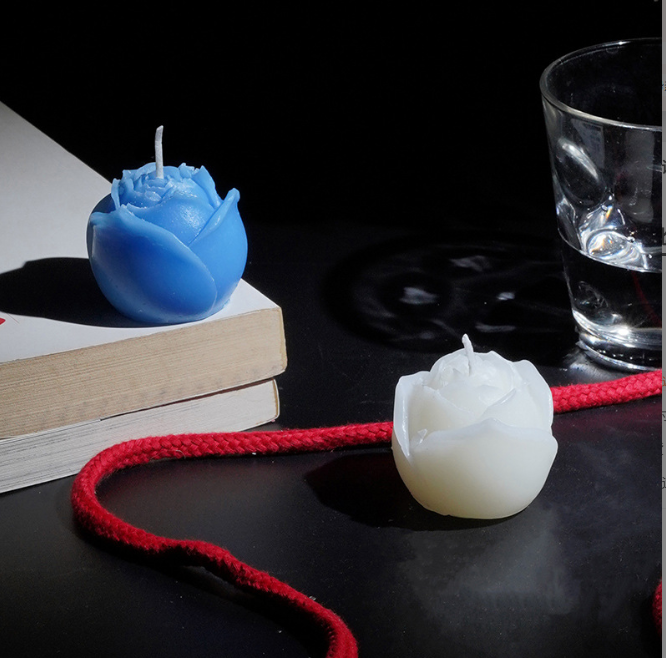 Low-Temperature Play Candle for couple BDSM - Blue and white rose-shaped candles on a table with rope and glass.
