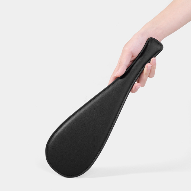 BDSM Spanking Toys Leather Paddles held in hand, showcasing its sleek black design and exquisite craftsmanship.
